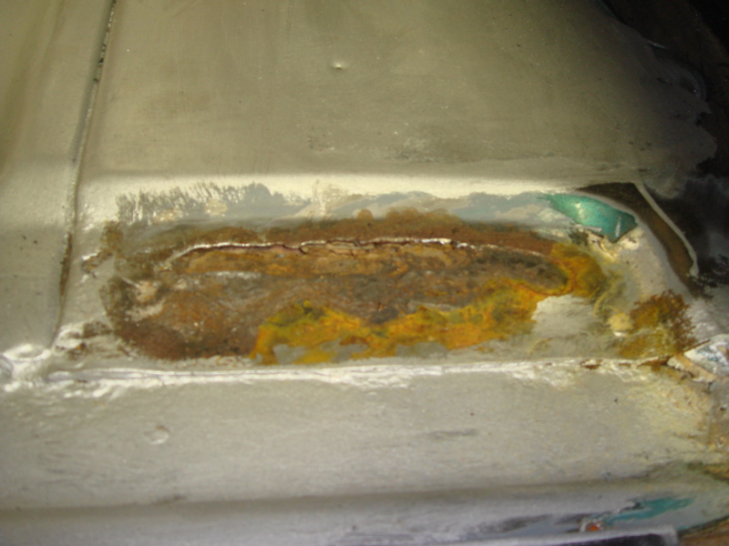 Rusted metal floor panel with crack and yellow staining