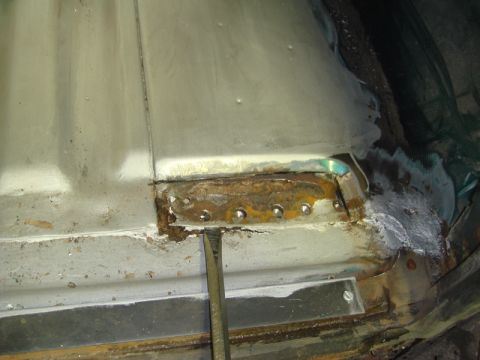 1996 Ford Bronco - Close-up of a rusted metal floor section being repaired with rivets and a chisel.