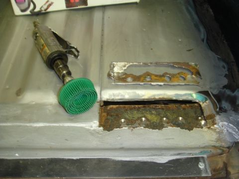 1996 Ford Bronco - Grinding tool and rusted metal panel, likely part of automotive floor repair.