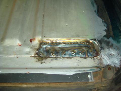 1996 Ford Bronco - Close-up of a welded patch on a vehicle's floor, showing the repair work and some discoloration.