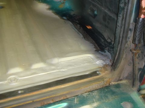 1996 Ford Bronco - Close-up view of a vehicle's interior floor showing rust treatment and protective coating application.