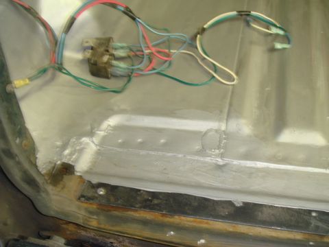 1996 Ford Bronco - Close-up of a vehicle's interior floor showing wiring and areas of rust and repair.