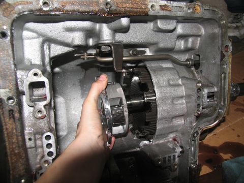 1978 Ford Bronco - A hand holds a clutch pack within the open casing of an automatic transmission, revealing internal gears and components.