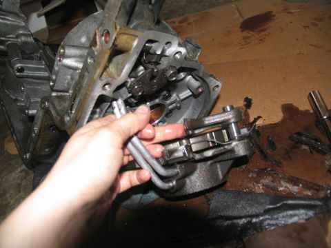 1978 Ford Bronco - A person's hand is shown working on a disassembled transmission part, with oil stains on the cardboard surface.