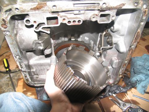 1978 Ford Bronco - A person is holding a disassembled transmission drum, revealing internal gears and casing components.