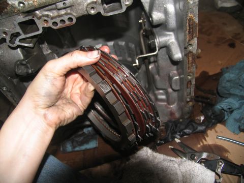 1978 Ford Bronco - A transmission clutch pack, showing worn friction plates, is held for inspection during a tear-down.