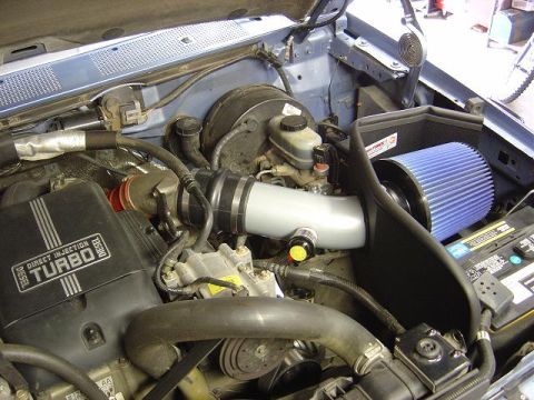 1986 Ford Bronco II - The engine bay features a turbo diesel engine with an upgraded air intake system and a blue air filter.