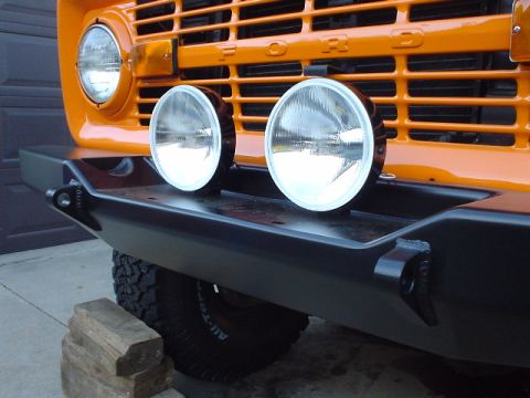 1977 Ford Bronco - Orange 1977 Ford Bronco front end with black aftermarket bumper and two round fog lights.