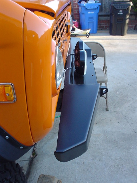 1977 Ford Bronco - Close-up view of the front bumper and headlight assembly on an orange 1977 Ford Bronco.