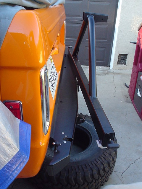 1977 Ford Bronco - Rear view of an orange 1977 Ford Bronco, an aftermarket spare tire carrier and a visible license plate.