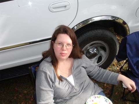 1989 Ford Bronco - A woman sits next to a white SUV during an outdoor event.