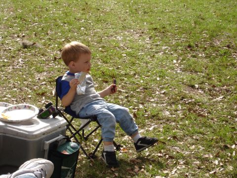 1989 Ford Bronco - A young child enjoys a snack while sitting in a folding chair at a picnic.