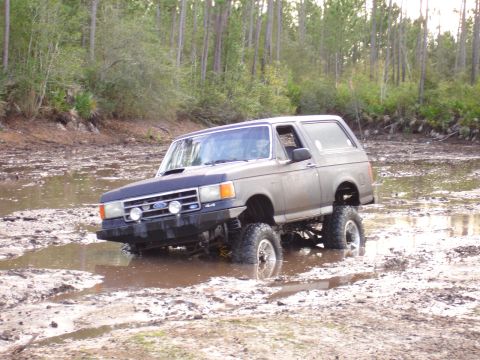 1989 Ford Bronco - Ford Bronco navigating a challenging muddy terrain during an off-road excursion.