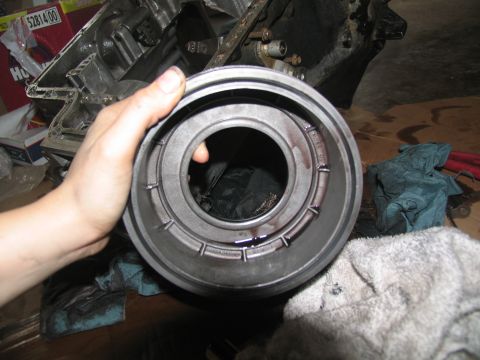 1978 Ford Bronco - A hand holds a transmission clutch drum, revealing internal components and dark fluid.