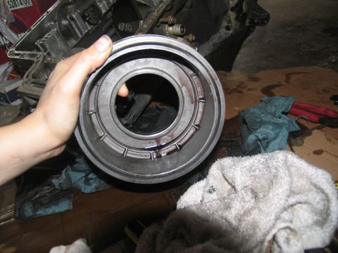 1978 Ford Bronco - A hand holds a transmission torque converter during a tear-down, revealing dark fluid within the component.