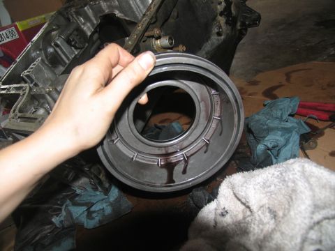 1978 Ford Bronco - Transmission part being held, with oil dripping onto rags and the floor.