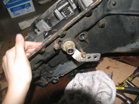 1978 Ford Bronco - A hand manipulates a linkage on a transmission component, with tools and a box of paper visible in the background.