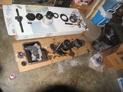 1978 Ford Bronco - Disassembled transmission components are spread out on cardboard, with tools and a cooler visible in the background.