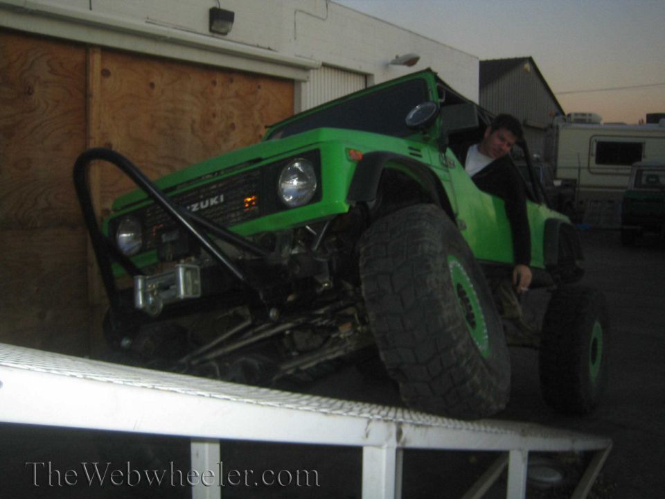 Green 1987 Suzuki Samurai on a ramp with large tires and a winch