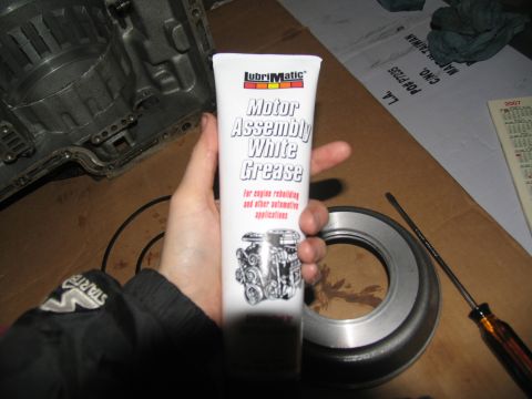 1978 Ford Bronco - Tube of white grease and transmission parts are laid out on a workbench.