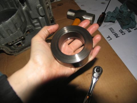 1978 Ford Bronco - A metal ring is held in a hand, with transmission parts and tools nearby.