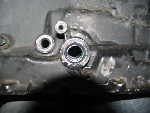 1978 Ford Bronco - A close-up view of a vehicle's transmission housing, showing various ports and fasteners. Some wear and tear are visible on the surface.