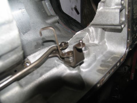 1978 Ford Bronco - A close-up view of a transmission component, showing a metal lever and linkage within a cast-iron casing.