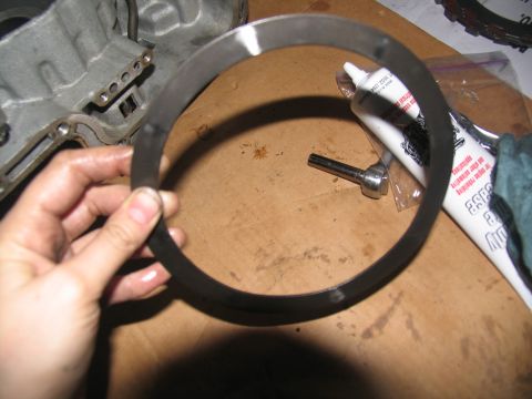 1978 Ford Bronco - A metal ring, likely a transmission part, is held by a hand over a workbench with tools and a grease tube.