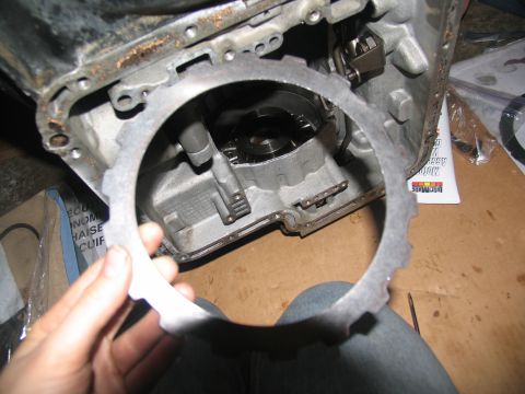1978 Ford Bronco - A clutch disc is held up to a transmission housing, likely during a rebuild.