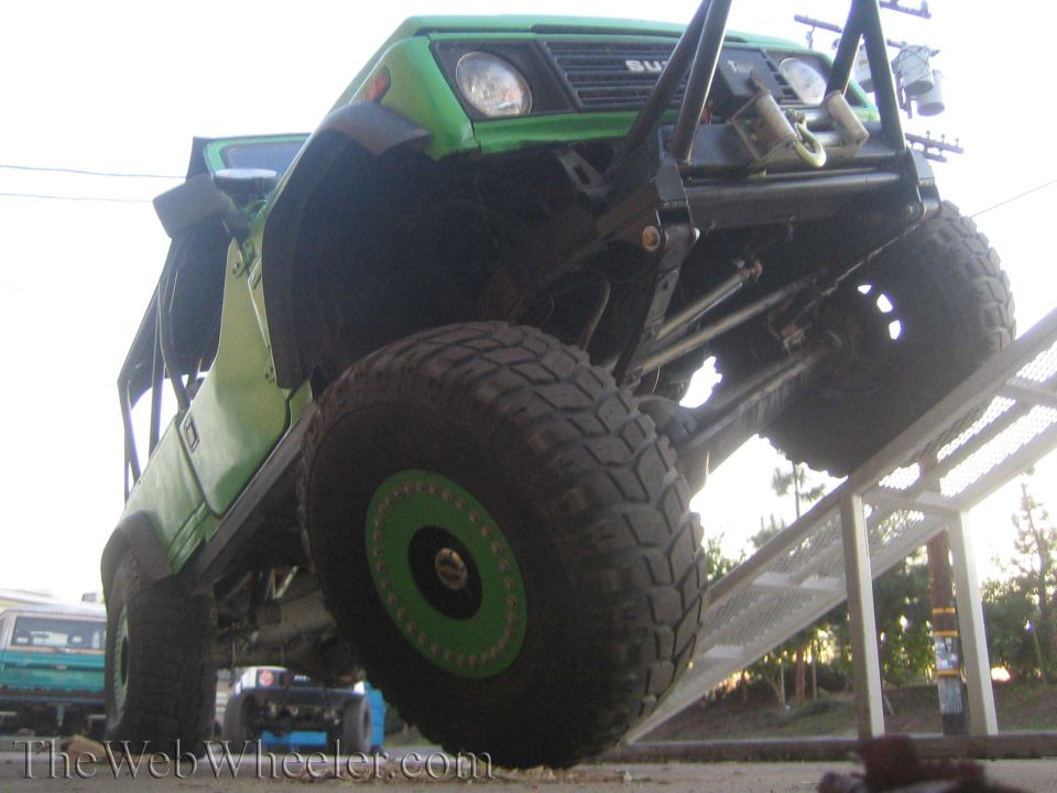 Green 1987 Suzuki Samurai on an RTI ramp with large off-road tires and a custom bumper