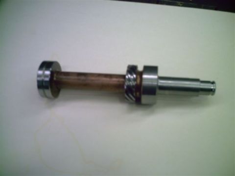 1964 Ford 427 - A metal shaft with bearings and a gear is shown against a white background.