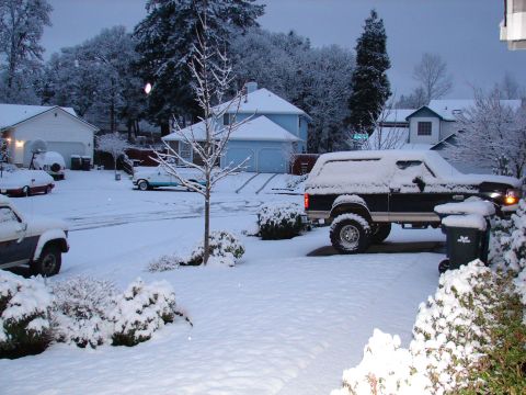 1996 Ford Bronco - A 1996 Ford Bronco sits covered in snow on a winter day, with houses and other cars in the background.
