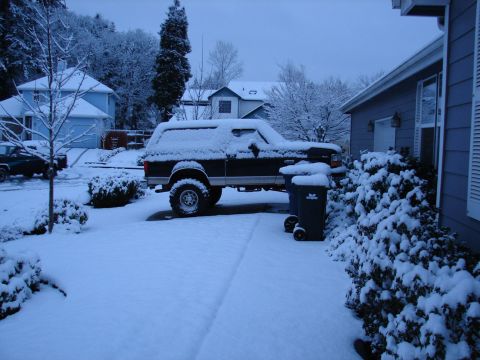 1996 Ford Bronco - A snow-covered Ford Bronco sits in a residential driveway during a winter storm.