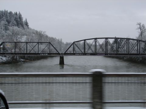 1996 Ford Bronco - A snow-covered landscape with a bridge spanning a river under a cloudy sky.