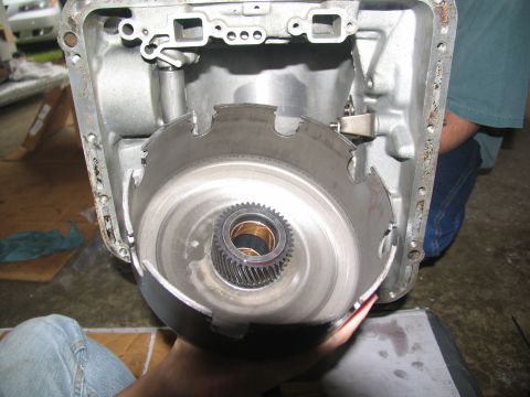 1978 Ford Bronco - Close-up of a transmission torque converter and its housing, held by hands.
