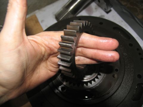 1978 Ford Bronco - A close-up shows a hand holding a metal gear, with another gear assembly in the background.