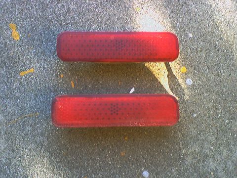 1973 Ford Ranchero - Two red reflectors are shown lying on a textured concrete surface.