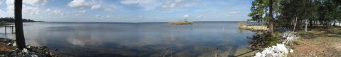 1986 Ford Bronco - A wide, panoramic view captures a tranquil lake with a small island in the distance and trees lining the right bank.