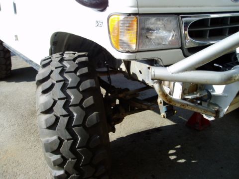 2000 Ford E350 - Front view of a white van modified with large off-road tires and a custom bumper. The body style indicates a 1992 model year.