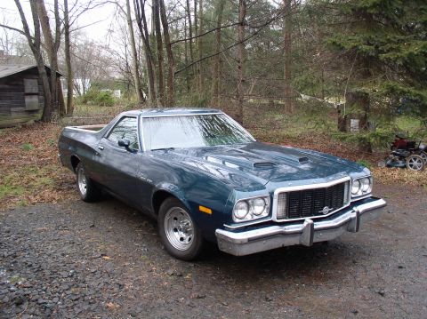 1973 Ford Ranchero - This 1973 Ford Ranchero features a distinctive grille and hood scoops, seen parked in a wooded area.