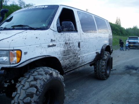 2000 Ford E350 - Modified 2000 Ford E350 van covered in mud, equipped with large off-road tires.