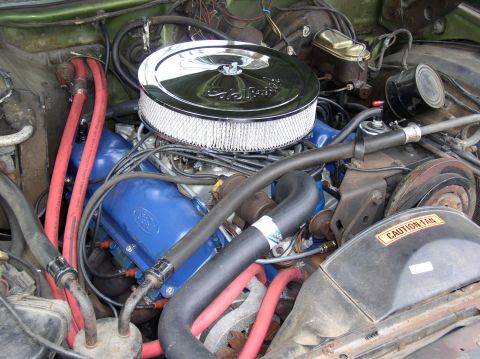 1973 Ford Ranchero - The engine bay shows a blue Ford V8 engine with a prominent chrome air filter assembly and red coolant hoses.