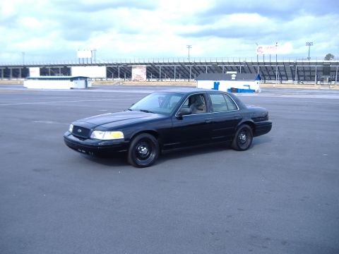 2001 Ford Crown Victoria - Black 2001 Ford Crown Victoria parked on asphalt in front of grandstands.