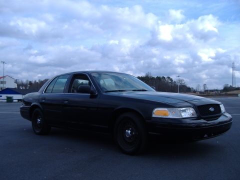 2001 Ford Crown Victoria - A black 2001 Ford Crown Victoria is parked outdoors under a cloudy sky.
