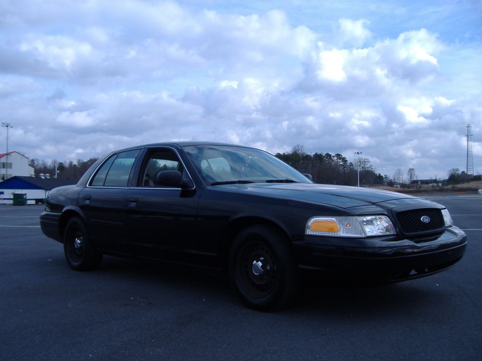 Black Ford Crown Victoria sedan, front 3/4 passenger side, black steel wheels