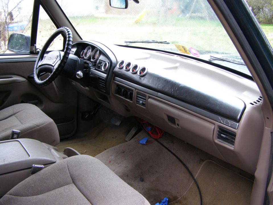 Interior of a 1993 Ford Bronco showing dashboard with aftermarket gauges and XLT trim