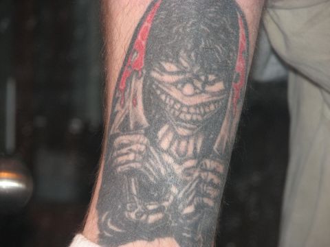 1991 Ford Bronco - Close-up of a tattoo depicting a menacing, grinning creature on a person's arm.
