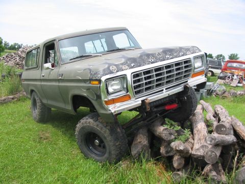1978 Ford Bronco - This lifted 1978 Ford Bronco features custom skull graphics on its hood and is shown navigating an obstacle of logs.
