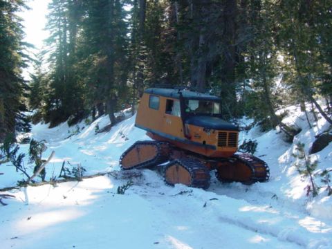 1986 Ford Bronco - A tracked vehicle navigates a snow-covered path through a forest.