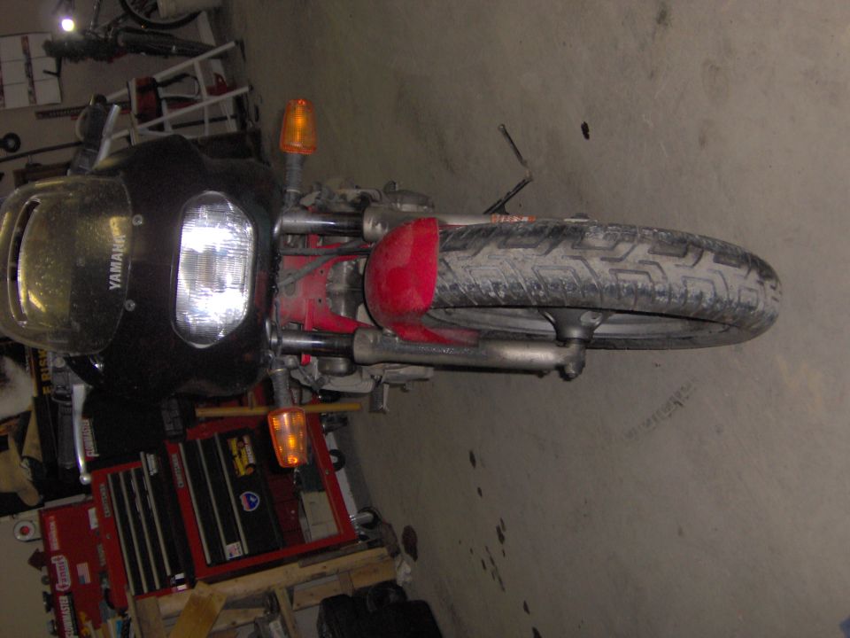 Front view of a black Yamaha motorcycle with red front fender in a garage